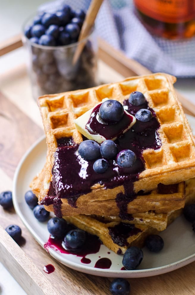 Blueberry syrup dripping off a stack of waffles.