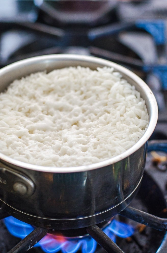 A pot of cooked white rice showing when to turn off the heat.