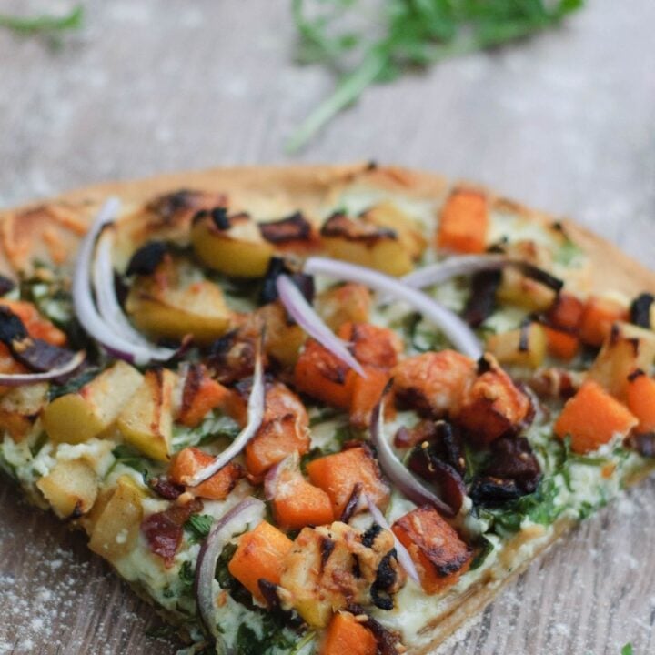 A slice of pizza with pumpkin and various other toppings