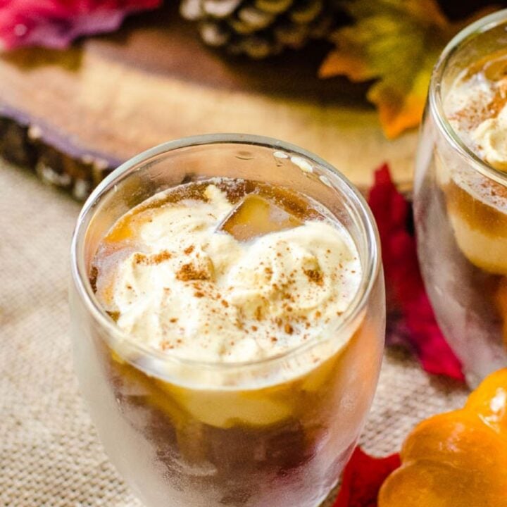 A glass cup filled with cold coffee topped with cream