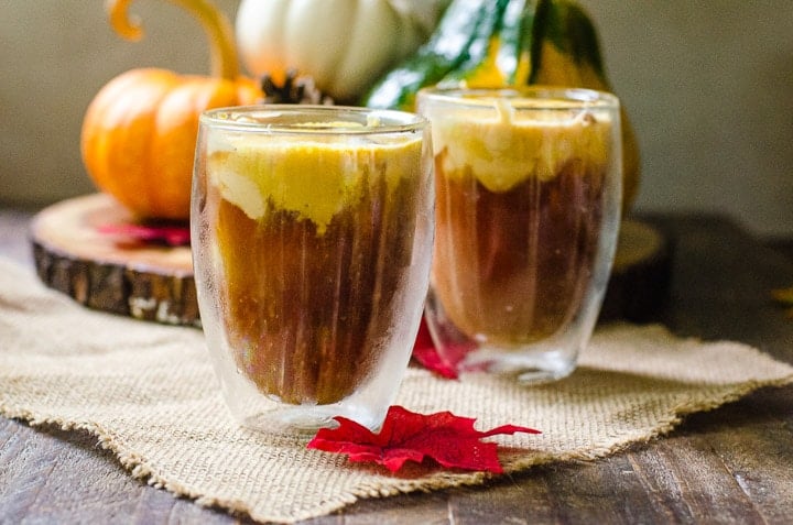 Two cups of pumpkin cream cold brew with cream streaming into the coffee.