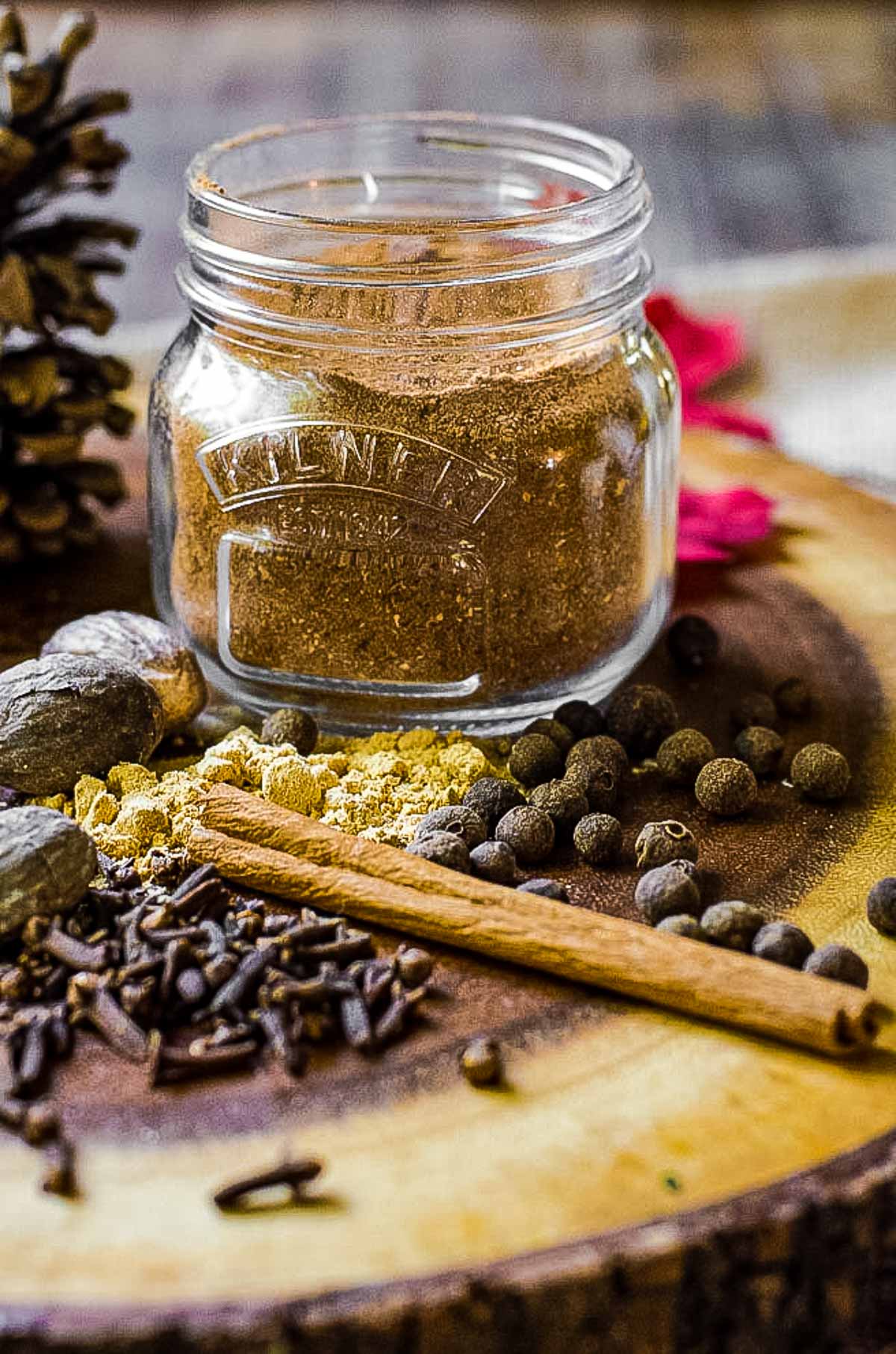 A jar of homemade pumpkin pie spice surrounded by whole spices.