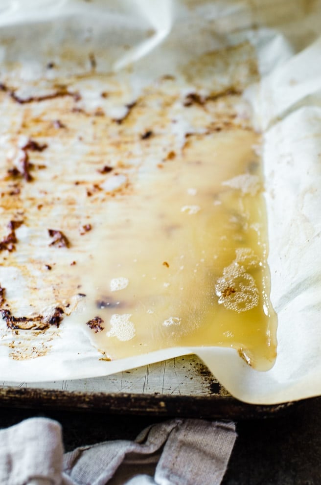 Bacon fat trapped by parchment paper on a sheet pan.