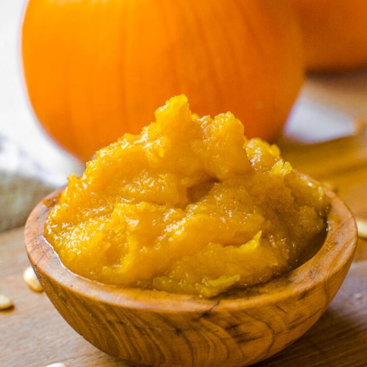 A wooden bowl filled with an orange pumpkin puree