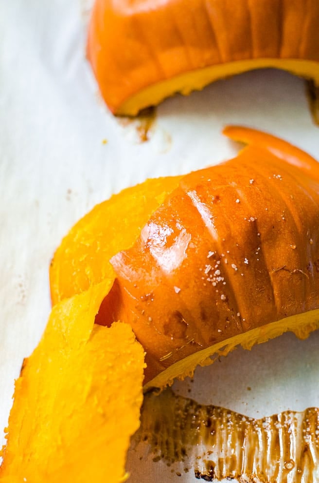 The pumpkin skin being peeled off of the roasted flesh. 