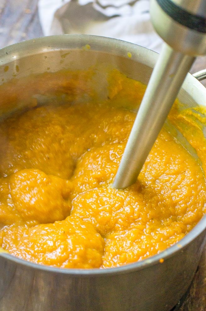 An immersion blender puréeing pumpkin soup.