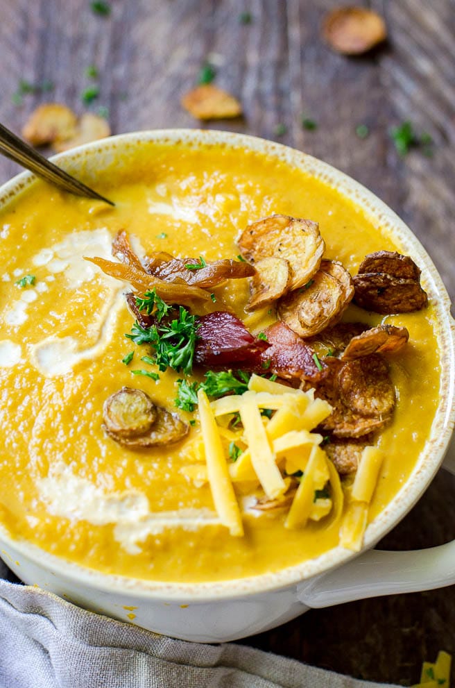 Close up of the drizzle of cream on pumpkin soup with a spoon coming out.