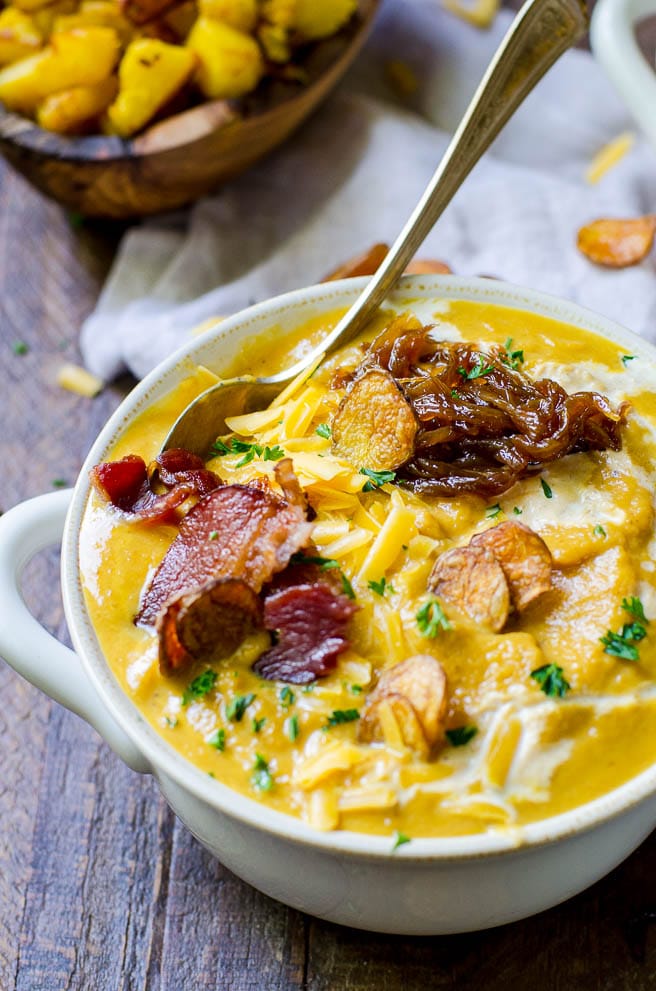Close up of bacon, potatoes, and cheese that are loaded onto pumpkin soup.  