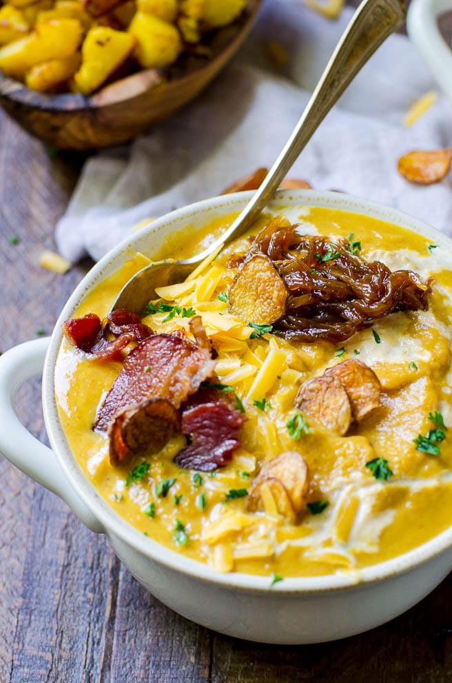 Close up of bacon, potatoes, and cheese that are loaded onto pumpkin soup.