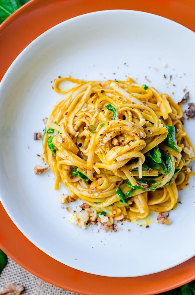 Overhead view of the toasted walnuts on top of creamy pumpkin pasta.