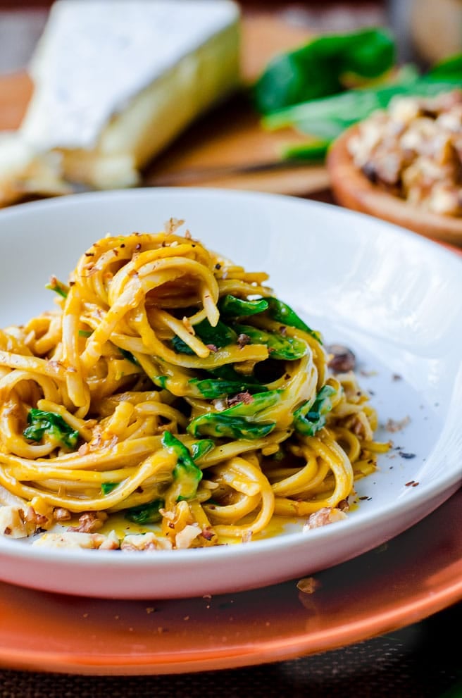 Linguine noodles and spinach piled up on a white plate.