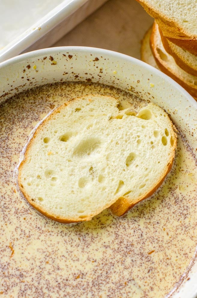 A slice of french bread floating in pumpkin french toast egg mixture.