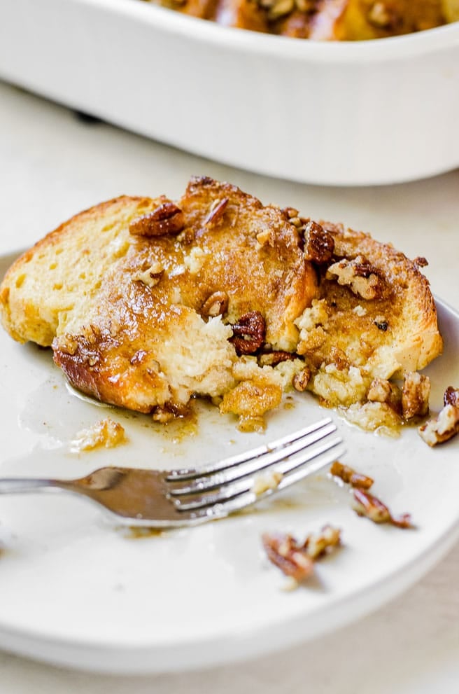 A fork next to french toast with a bite taken out of it.