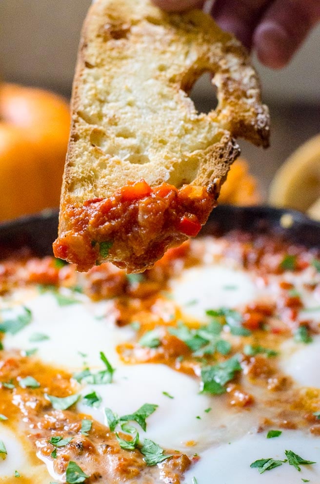 A close up of tomato stew on a piece of crusty bread