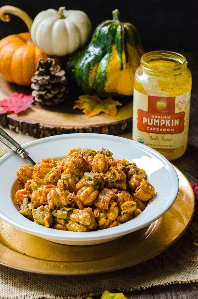 A bowl of zucchette pasta next a jar of pumpkin pasta sauce.