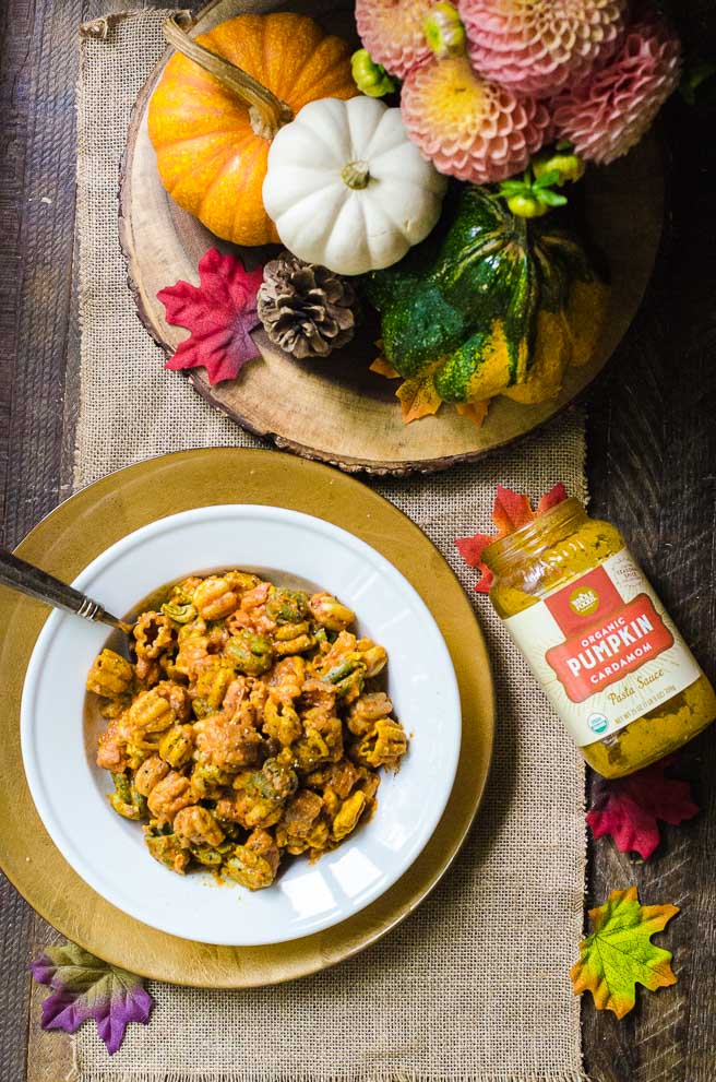 An autumnal table set for dinner with a bowl of pasta and a jar of fall flavor pasta sauce.