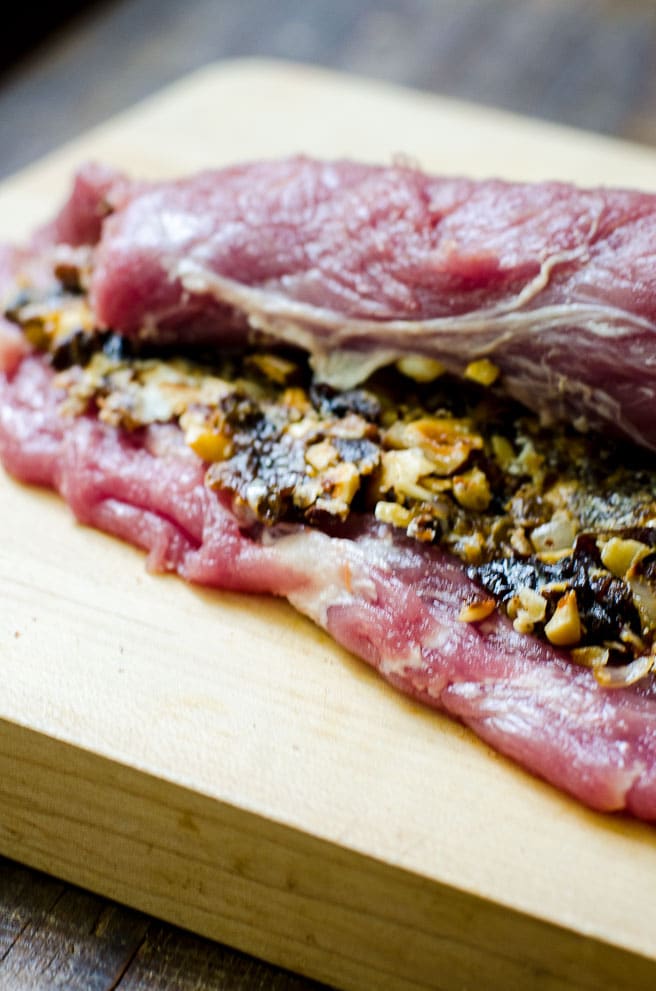 Butterflied pork tenderloin being rolled up for a roulade.