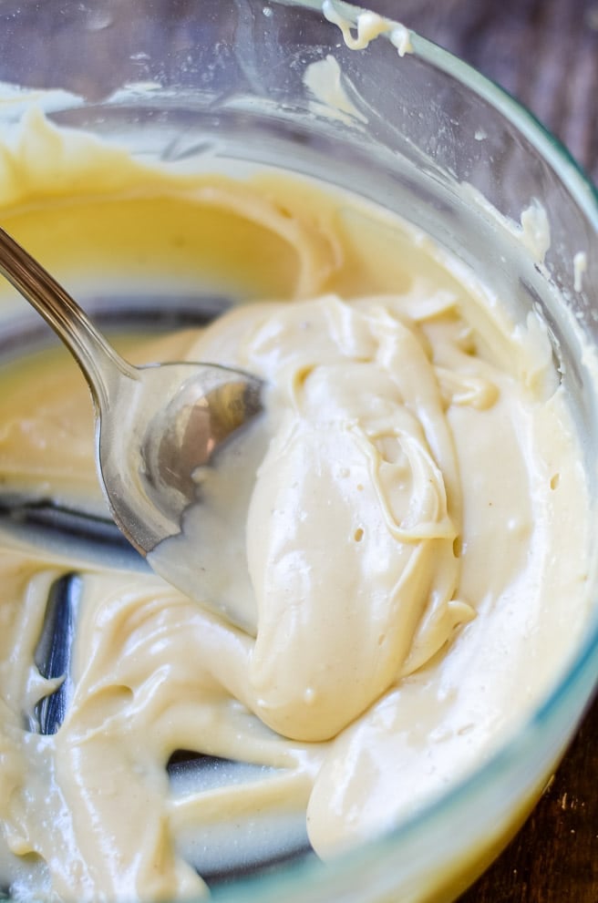 Brown butter icing being stirred in a bowl.