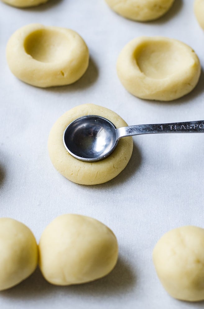 A teaspoon making an even indentation in cookie dough.