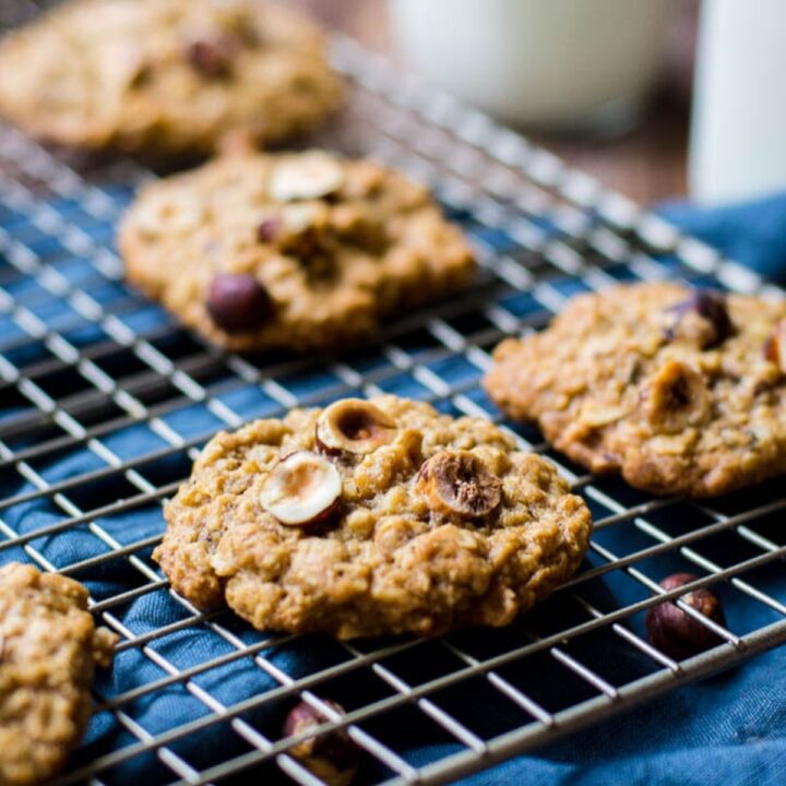 A cooling rack holding freshly made cookies filled with oatmeal oats, raisins and more