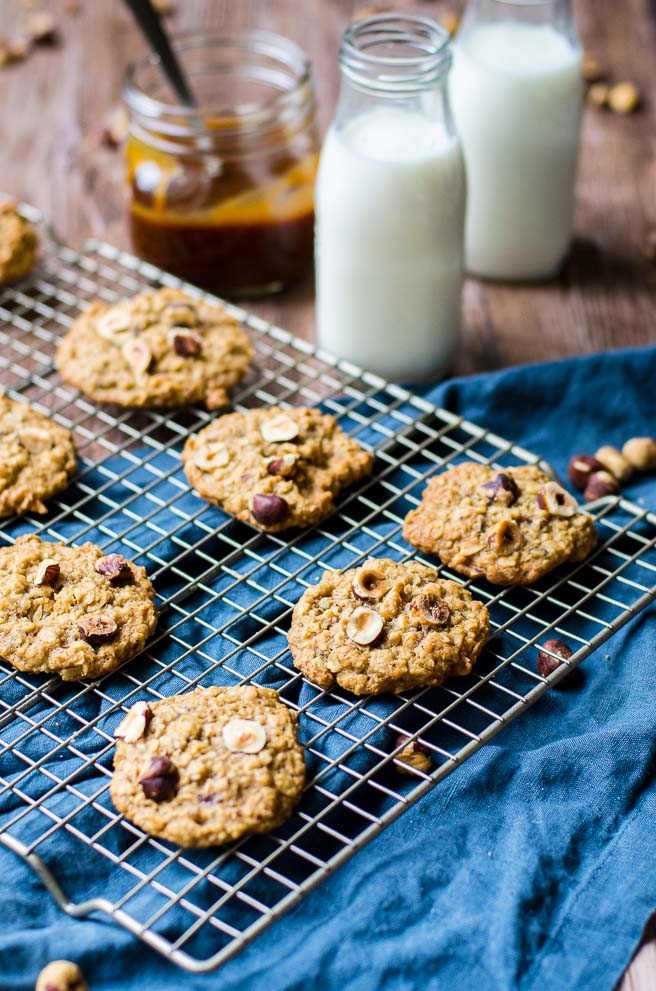 A cooling rack of chewy hazelnut cookies next to containers of milk.