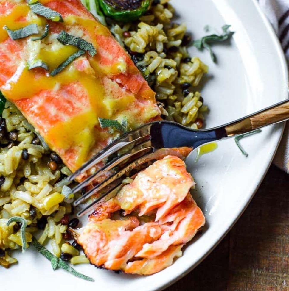 A fork cutting into sous vide salmon on a bed of rice.