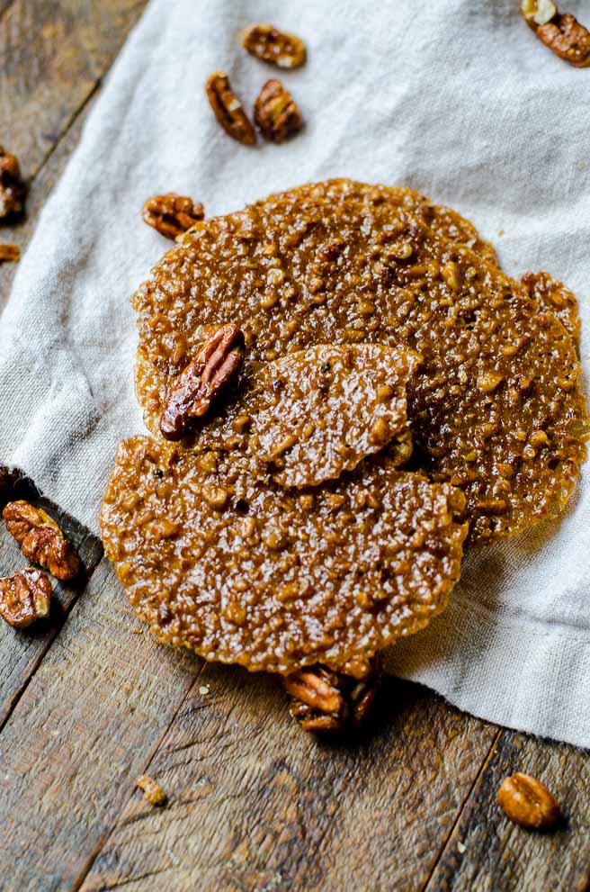 Pecans and lace bookies on a gray napkin.