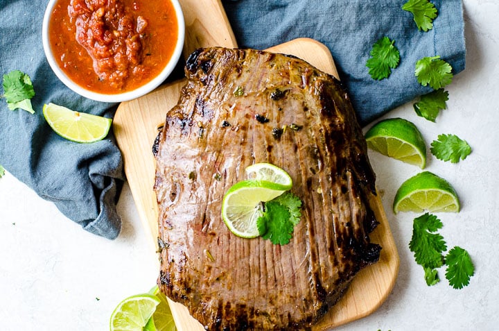 A two pound broiled flank steak on a cutting board.