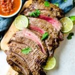 Sliced carne asada meat on a cutting board. It is cooked to medium rare.
