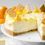 Creamy lemon curd dripping off the side of a meyer lemon cheesecake that is sliced.