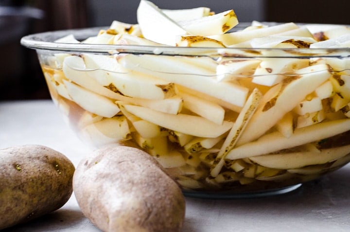 Cut potatoes soaking in a bowl before frying into french fries.