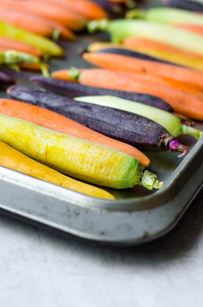 Peeled rainbow carrots on a sheet pan before roasting.