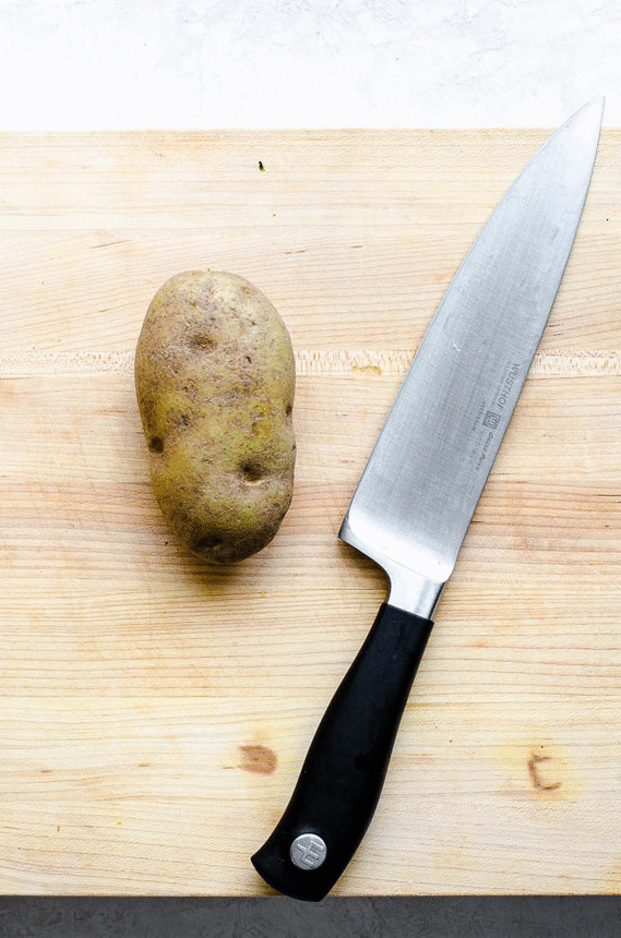 A gif showing how to use a knife to cut a potato into homemade french fries.