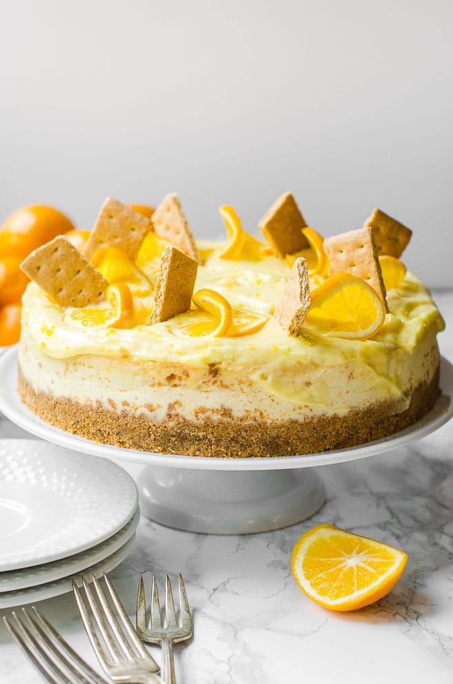 A whole Meyer lemon cheesecake on a serving stand ready to serve.