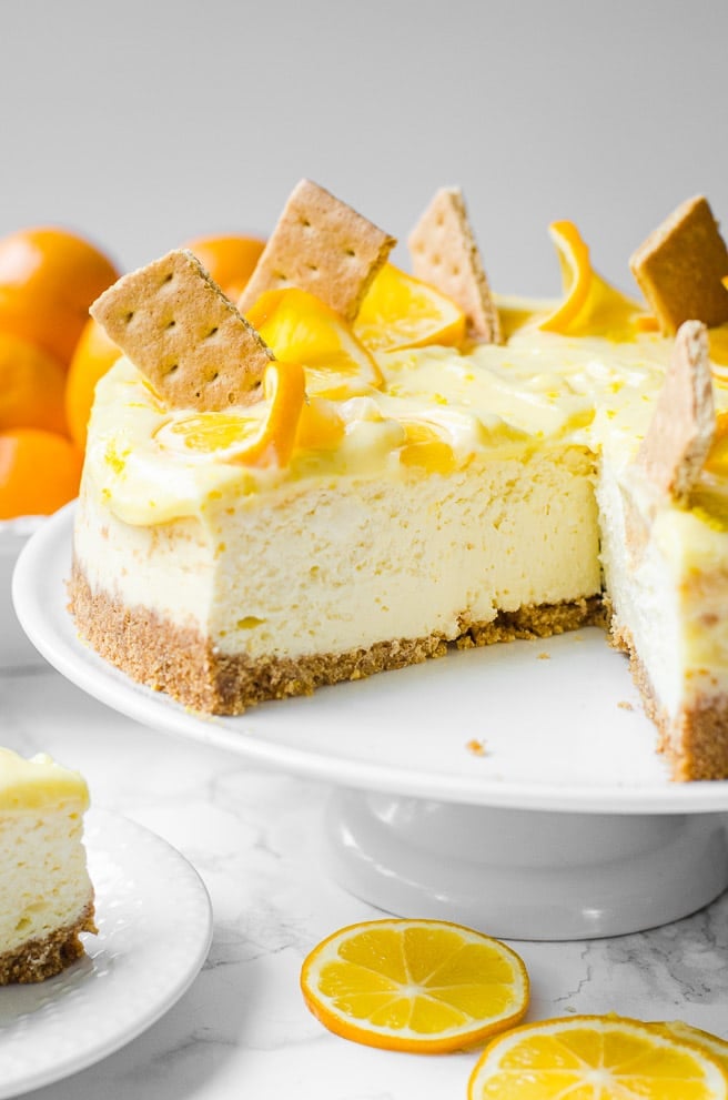 Meyer Lemon Cheesecake on a white stand with a piece removed for eating.