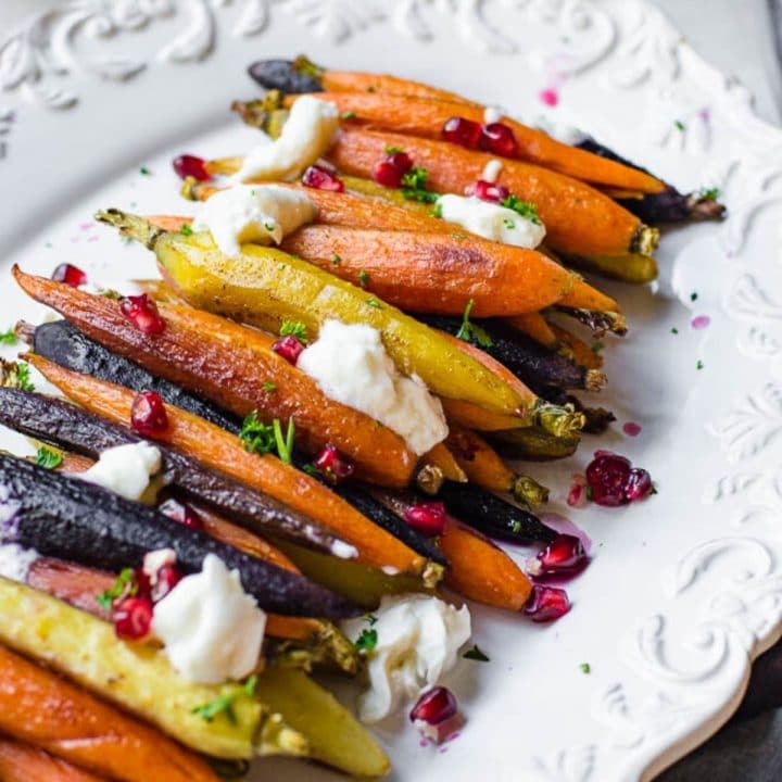 A white platter with rainbow honey roasted carrots lined up.