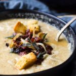 Close up of the bacon and caramelized onion garnish in a bowl of roasted cauliflower soup.