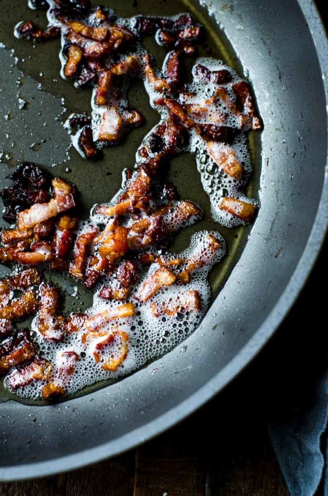Pieces of bacon sizzling in a pan.