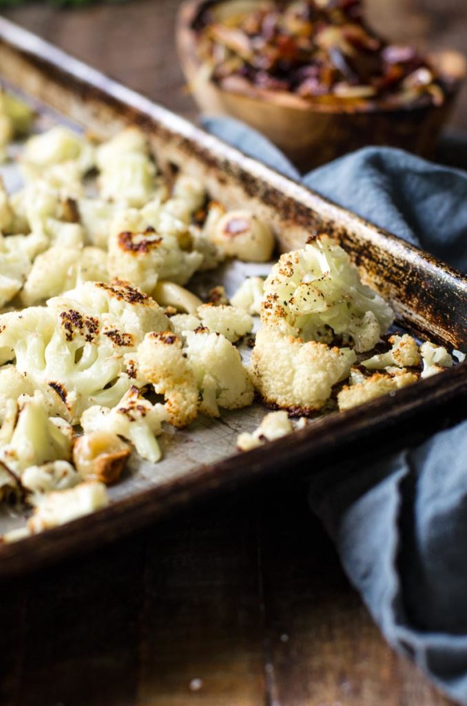 A baking sheet of golden brown roasted cauliflower and garlic.
