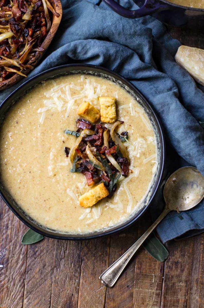 Overhead view of a bowl of roasted cauliflower soup next to a bowl of garnish.