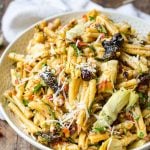 A large bowl of sun dried tomato pasta salad with California prunes garnished with cheese.