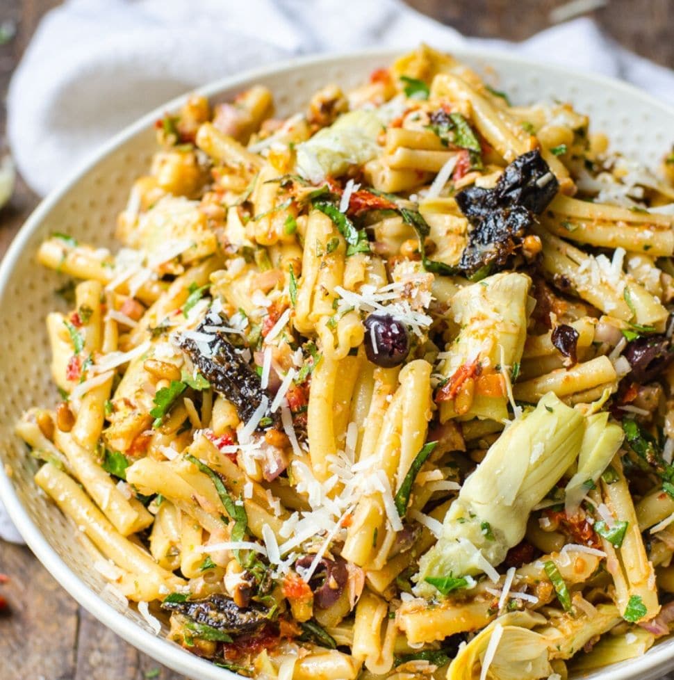 A large bowl of sun dried tomato pasta salad with California prunes garnished with cheese.