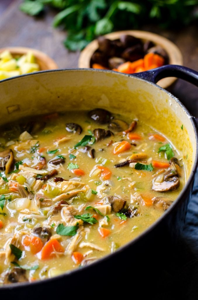 A purple dutch oven filled with leftover turkey vegetable soup.