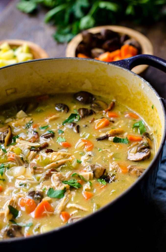 A purple dutch oven filled with leftover turkey vegetable soup.