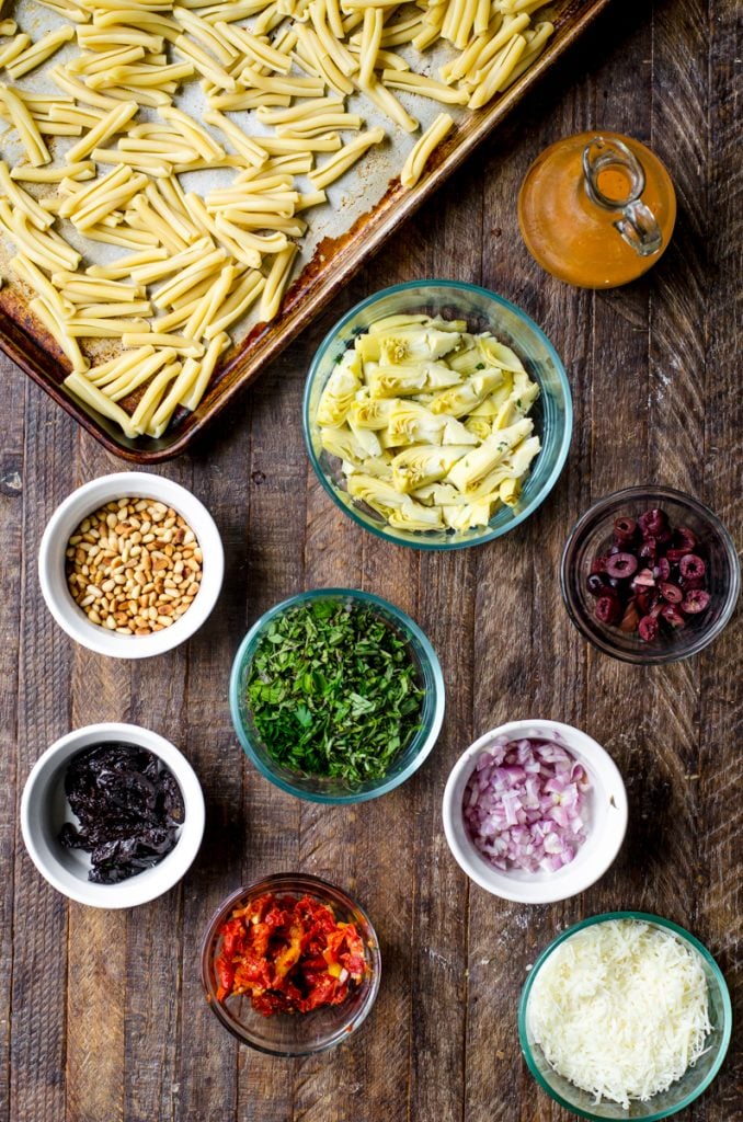 Overhead view of ingredients in individual bowls for making sun dried tomato pasta salad.