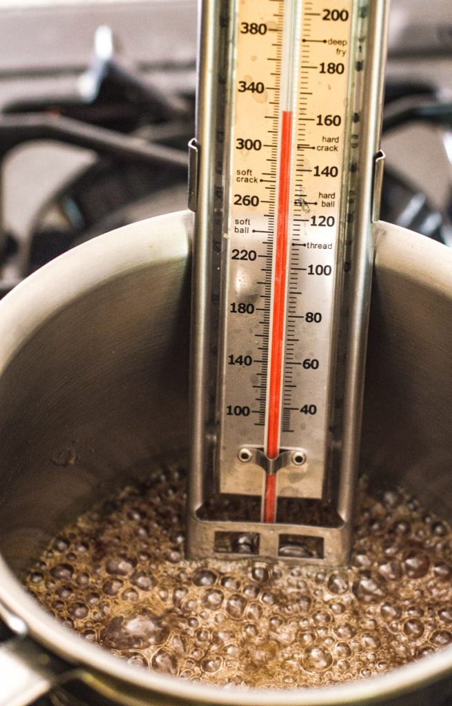 A candy thermometer inside a pot making salted caramel.