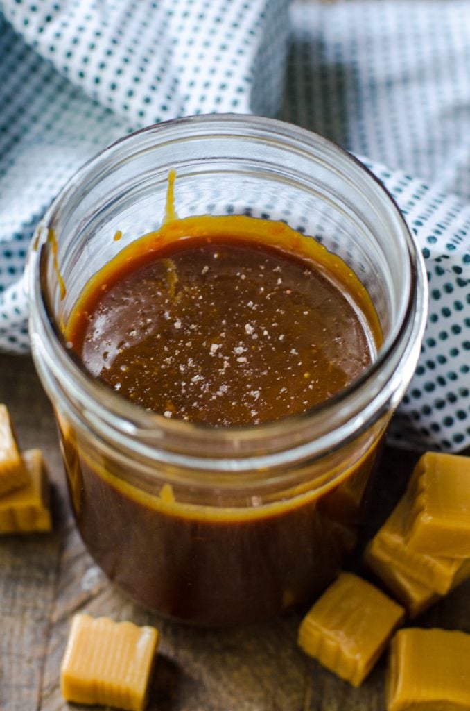A mason jar of homemade salted caramel sauce focusing on the salt.