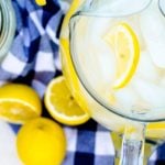 Overhead view of a pitcher of reconstituted frozen lemonade concentrate on a blue checkered napkin.