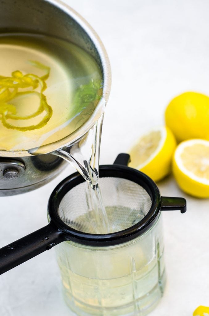 Lemon syrup being strained into a glass.