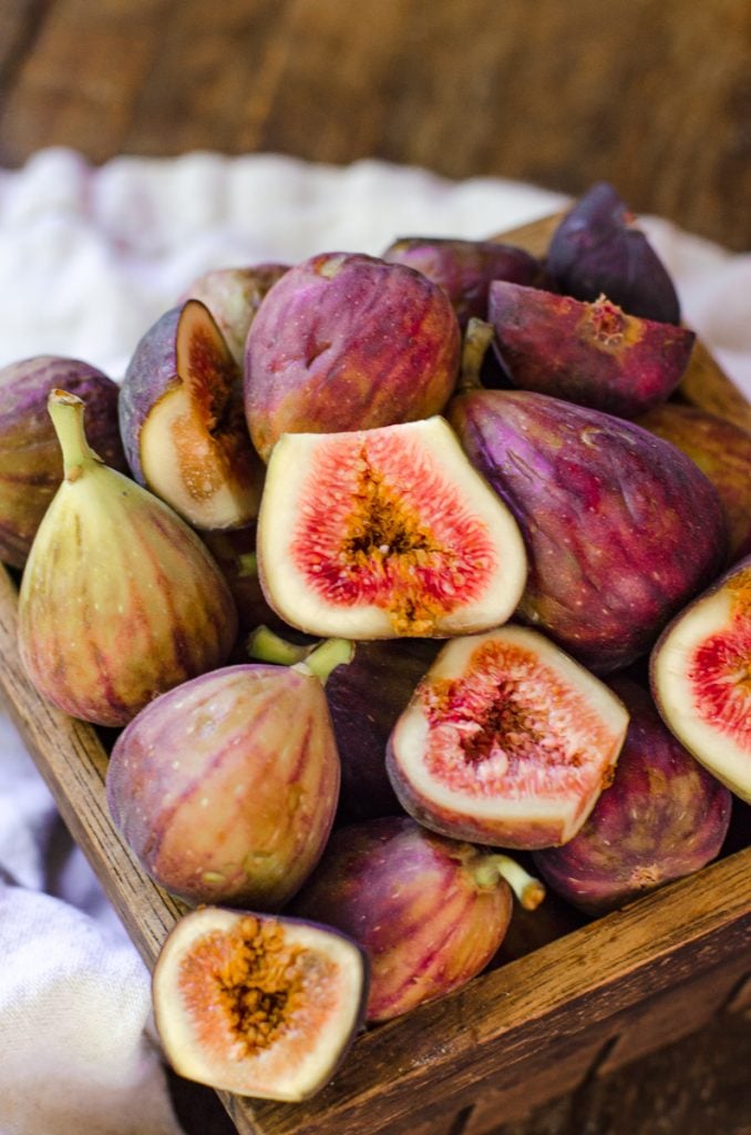 Close up of a basket of figs. Some are cut in half, others are whole.
